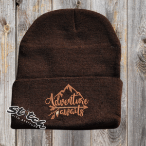 Dark brown beanie with adventure awaits embroidered on it