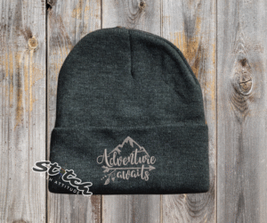 Charcoal beanie with adventure awaits embroidered on it