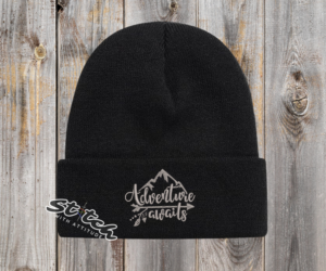 Black beanie with adventure awaits embroidered on it