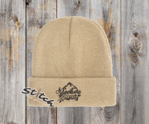 Tan beanie with adventure awaits embroidered on it