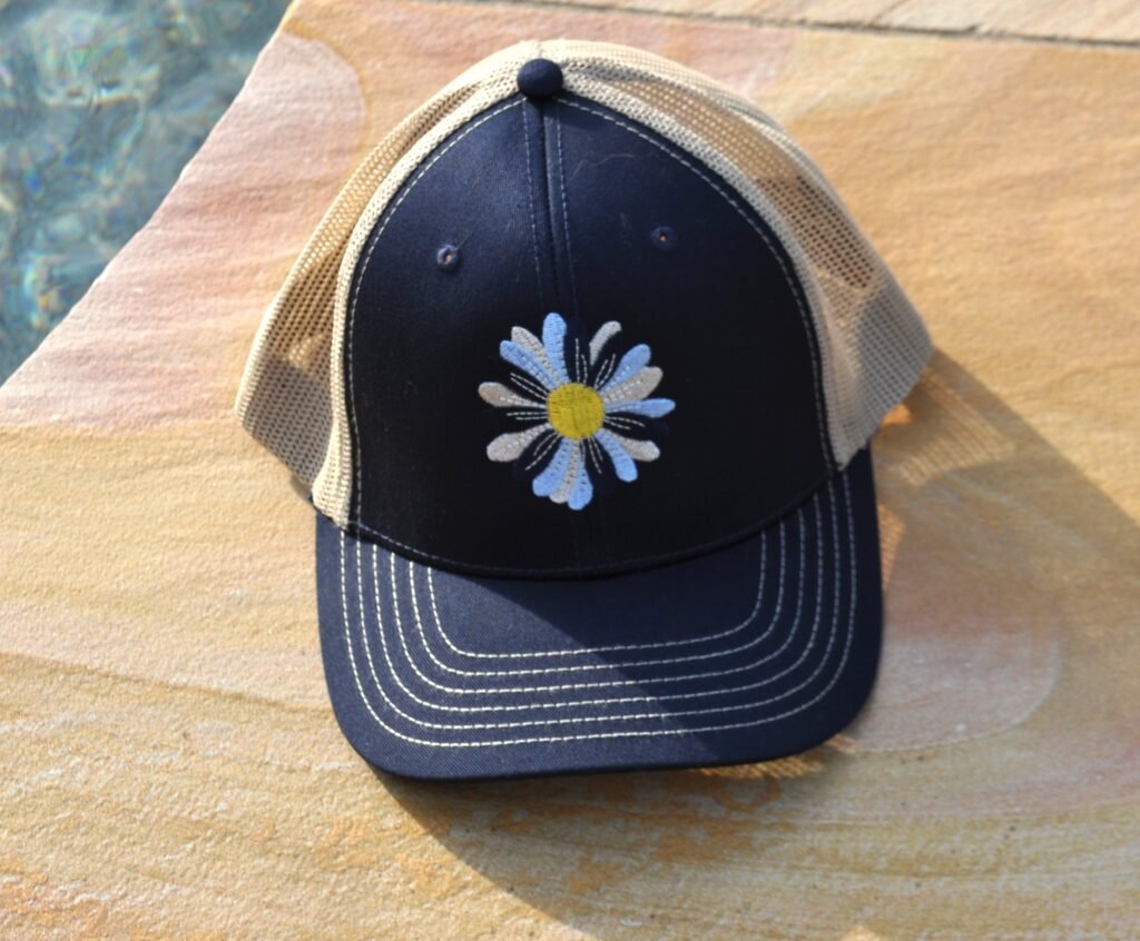 Navy and tan hat with a multi-blue flower