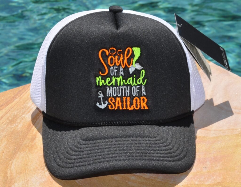 Black and white foam trucker hat with "Sour of a mermaid mouth of a sailor" embroidered on the front