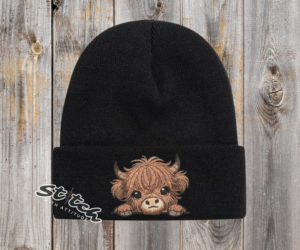 Baby highland cow on a black beanie