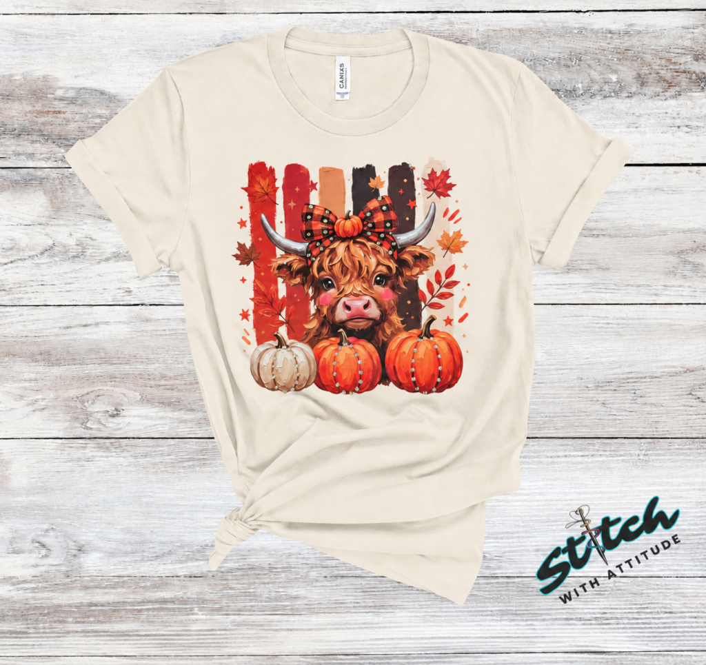 Highland Cow Fall Pumpkin Rhinestone Tee. A shaggy little cow in a plaid bow, three pumpkins, and real rhinestones set by hand. Fall, wearing it loudly.