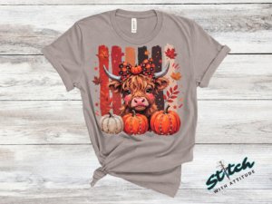 Highland Cow Fall Pumpkin Rhinestone Tee. A shaggy little cow in a plaid bow, three pumpkins, and real rhinestones set by hand. Fall, wearing it loudly.