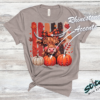 Highland Cow Fall Pumpkin Rhinestone Tee. A shaggy little cow in a plaid bow, three pumpkins, and real rhinestones set by hand. Fall, wearing it loudly.