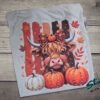 Highland Cow Fall Pumpkin Rhinestone Tee. A shaggy little cow in a plaid bow, three pumpkins, and real rhinestones set by hand. Fall, wearing it loudly.