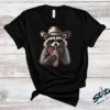 Cowboy Raccoon Rhinestone Tee - Cowboy-Raccoon-Rhinestone-Tee-01.png Cowboy Raccoon Rhinestone Tee. A raccoon in a cowboy hat, sunglasses and bandana, sipping from a leopard print cup. DTF print on black with rhinestones set by hand, standard or ext