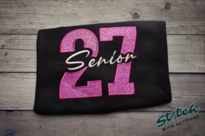 Senior 2027 Glitter Sweatshirt photo Senior 2027 glitter sweatshirt, folded, pink glitter 27 with Senior embroidered in white script