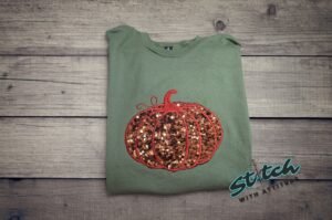 Sequin Pumpkin Applique Sweatshirt Sequin pumpkin applique fall sweatshirt with embroidered stem on a green garment